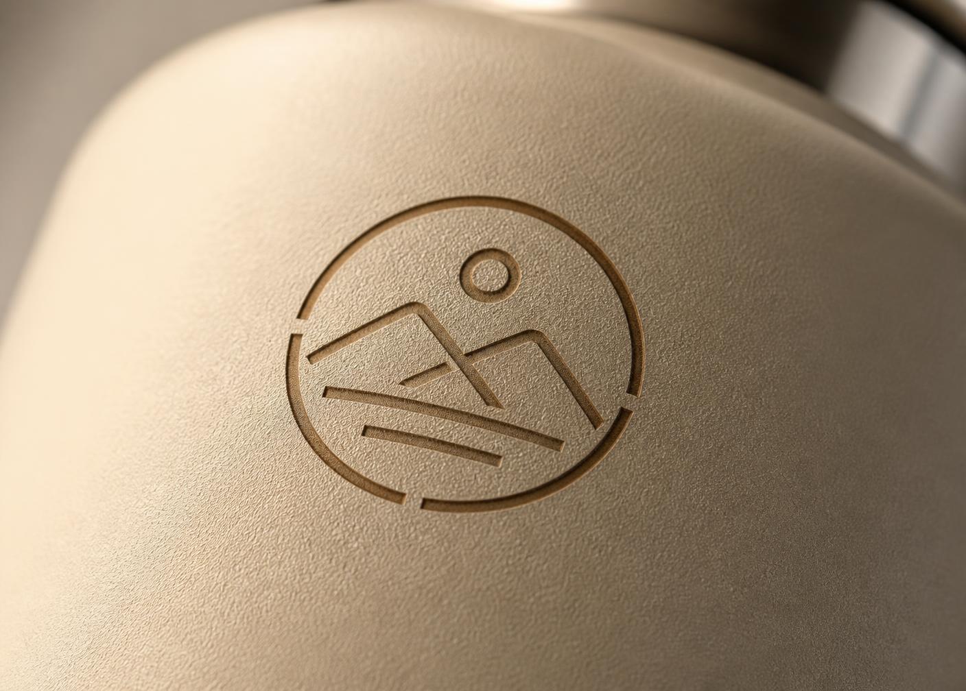 Close-up of an engraved logo mark on a matte bottle surface